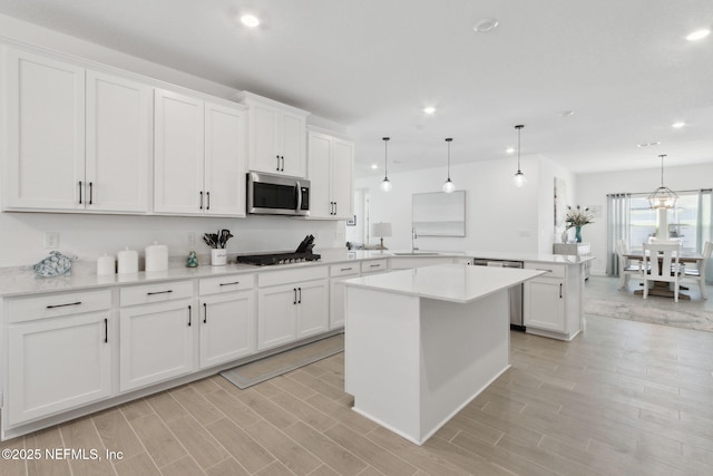 kitchen with white cabinets, kitchen peninsula, stainless steel appliances, and pendant lighting