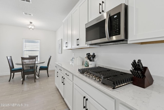 kitchen featuring light stone counters, white cabinets, and appliances with stainless steel finishes