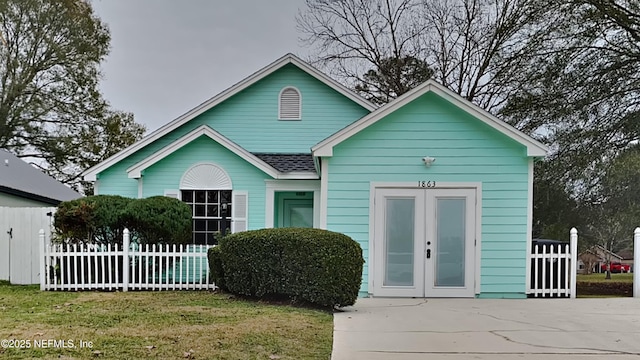 bungalow-style home featuring a front lawn and french doors