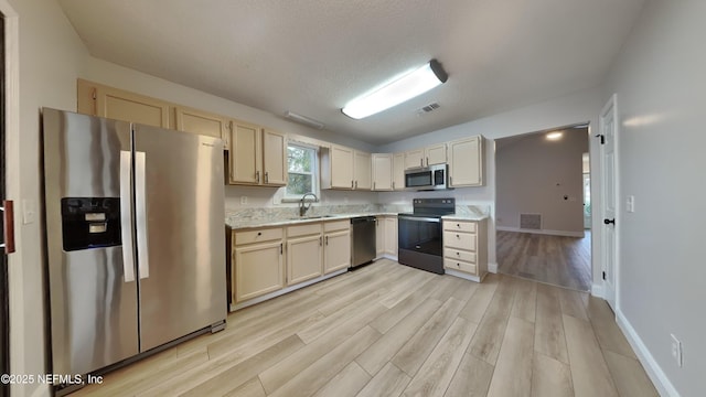 kitchen featuring a textured ceiling, stainless steel appliances, light hardwood / wood-style floors, and sink