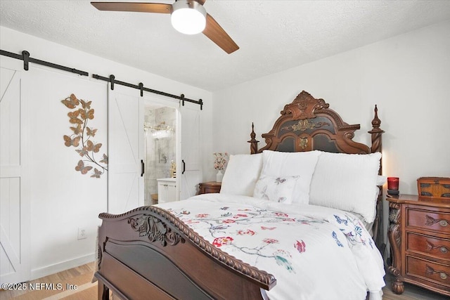 bedroom with light hardwood / wood-style flooring, a barn door, and a textured ceiling