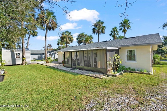 rear view of property with a yard, a storage unit, and a sunroom