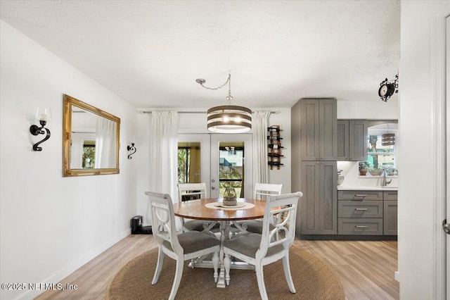 dining space with a healthy amount of sunlight, sink, light hardwood / wood-style floors, and a textured ceiling