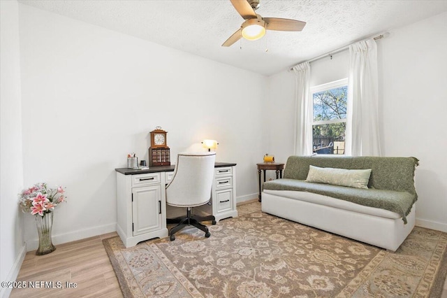 office space with ceiling fan, a textured ceiling, and light wood-type flooring