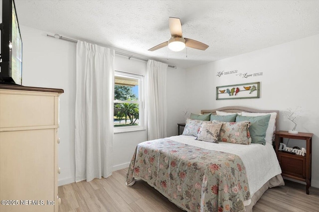 bedroom with ceiling fan, a textured ceiling, and light wood-type flooring