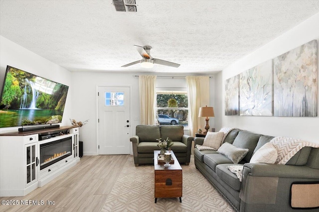 living room featuring a textured ceiling, light hardwood / wood-style flooring, and ceiling fan