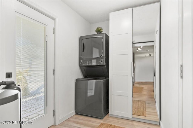 laundry area featuring stacked washer / drying machine and light hardwood / wood-style flooring