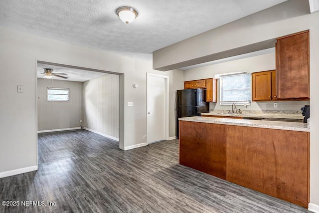 kitchen featuring kitchen peninsula, ceiling fan, dark hardwood / wood-style floors, black fridge, and a textured ceiling