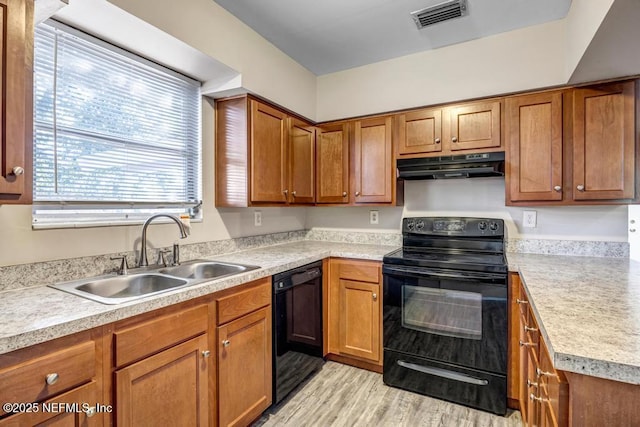 kitchen featuring black appliances, sink, and light hardwood / wood-style flooring