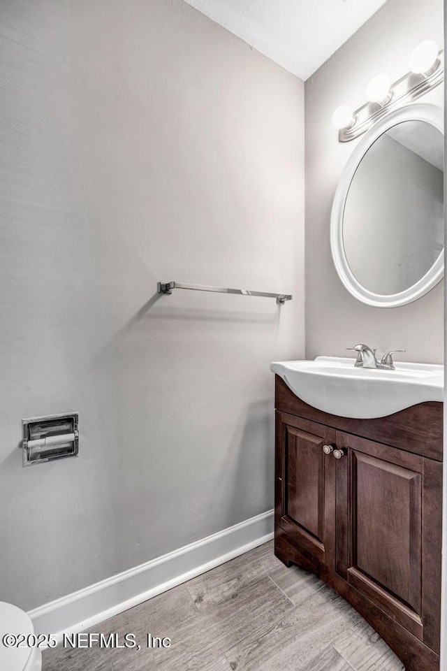 bathroom featuring toilet, wood-type flooring, and vanity