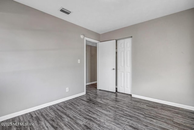 unfurnished bedroom featuring a closet and dark hardwood / wood-style floors