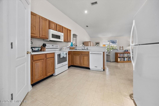 kitchen featuring sink, lofted ceiling, kitchen peninsula, and white appliances