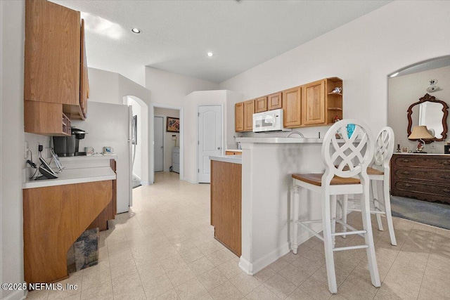 kitchen with refrigerator, kitchen peninsula, and a breakfast bar