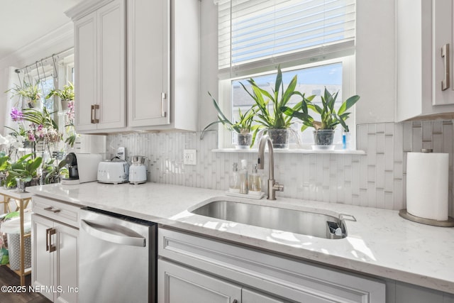 kitchen featuring sink, dishwasher, white cabinets, light stone countertops, and backsplash