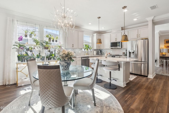 dining area with ornamental molding, dark hardwood / wood-style flooring, sink, and a notable chandelier