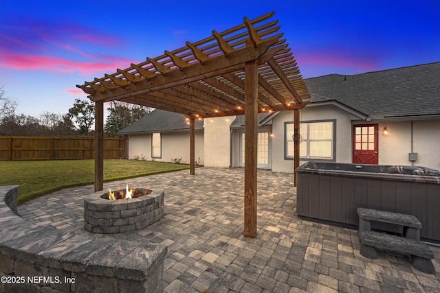 patio terrace at dusk with a hot tub, a fire pit, a yard, and a pergola