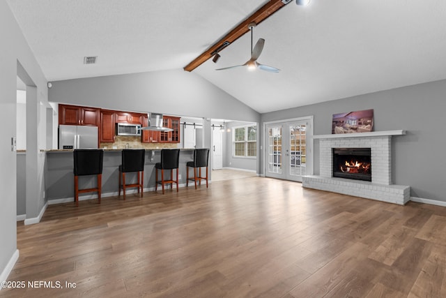 living room with a fireplace, light hardwood / wood-style floors, lofted ceiling with beams, and ceiling fan