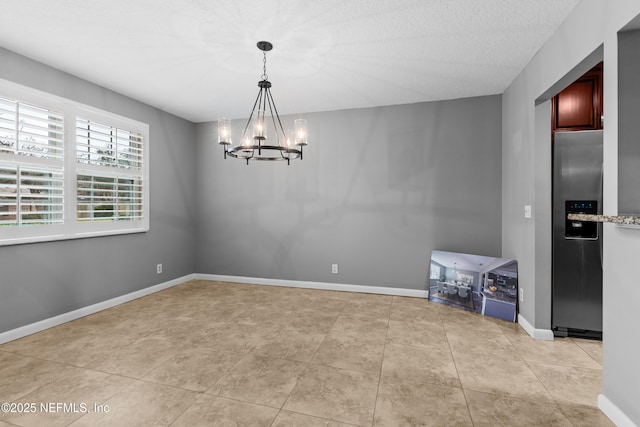 tiled empty room featuring a notable chandelier and a textured ceiling