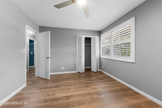 unfurnished bedroom featuring ceiling fan, a textured ceiling, and light wood-type flooring