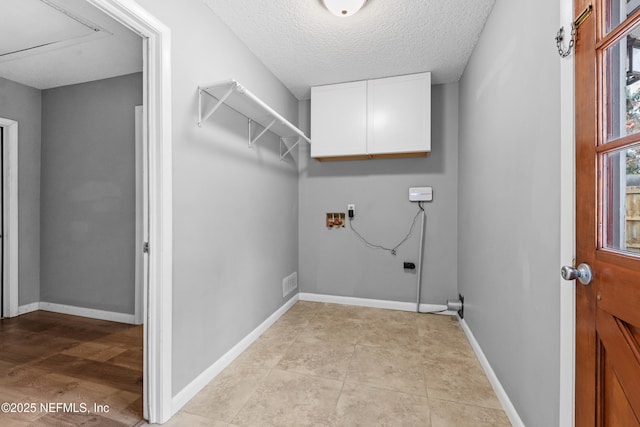 washroom featuring cabinets, a textured ceiling, and hookup for a washing machine