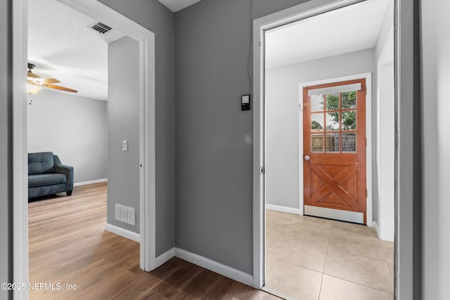 hallway with light hardwood / wood-style floors and a textured ceiling