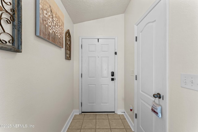 entryway with vaulted ceiling, a textured ceiling, and light tile patterned flooring