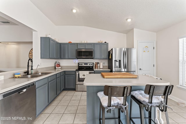 kitchen with appliances with stainless steel finishes, sink, a kitchen breakfast bar, a center island, and light tile patterned floors