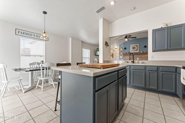 kitchen with sink, decorative light fixtures, light tile patterned flooring, and a kitchen island