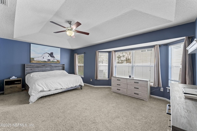 bedroom with a raised ceiling, light colored carpet, and multiple windows