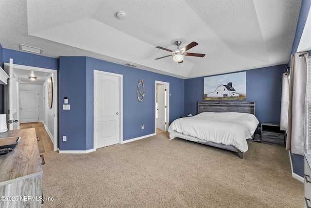 carpeted bedroom featuring ceiling fan, a tray ceiling, vaulted ceiling, and a textured ceiling