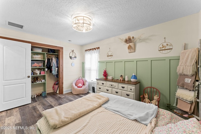 bedroom with dark wood-type flooring, a closet, and a textured ceiling