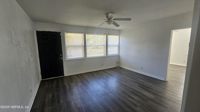 spare room with dark wood-style floors, ceiling fan, and baseboards