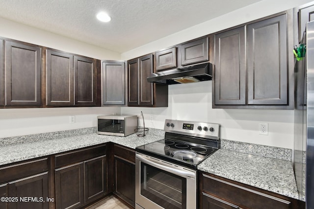 kitchen with a textured ceiling, stainless steel appliances, dark brown cabinetry, and light stone countertops