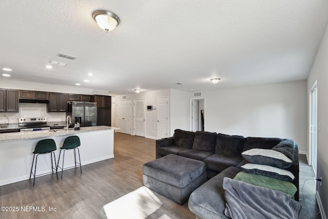 living room with sink, a textured ceiling, and dark hardwood / wood-style floors