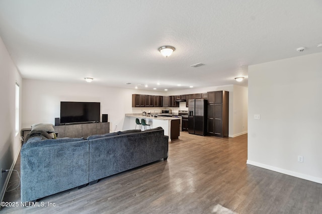 living room featuring wood-type flooring, sink, and a textured ceiling