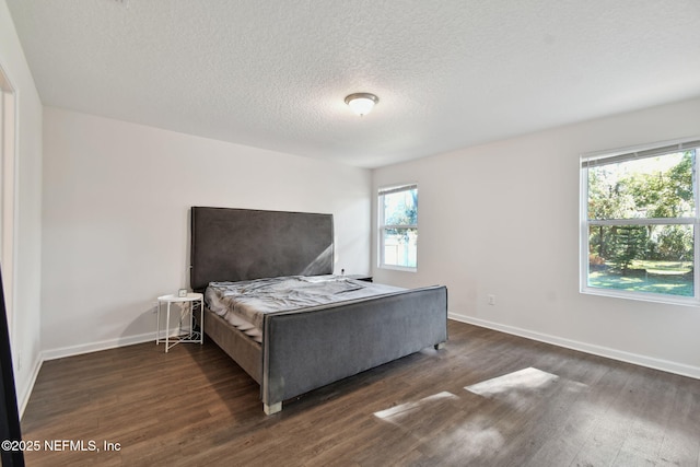 bedroom featuring a textured ceiling, dark hardwood / wood-style floors, and multiple windows