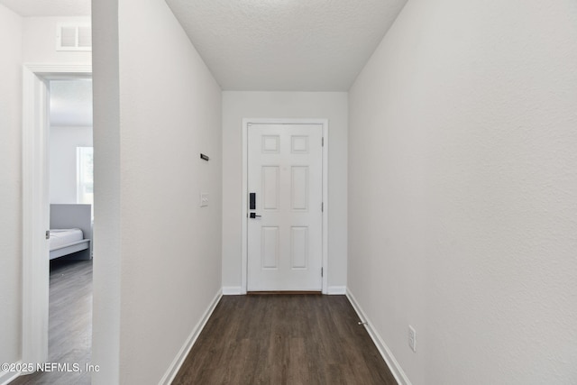 corridor with dark hardwood / wood-style flooring and a textured ceiling