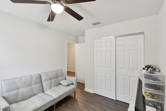 living area with a textured ceiling, ceiling fan, and dark hardwood / wood-style floors