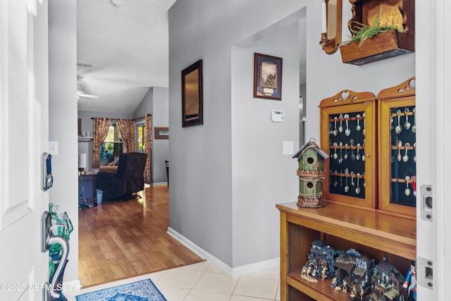 hallway with vaulted ceiling and light tile patterned flooring