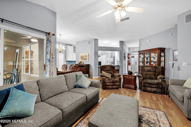 living room featuring light wood-type flooring, a textured ceiling, and ceiling fan with notable chandelier