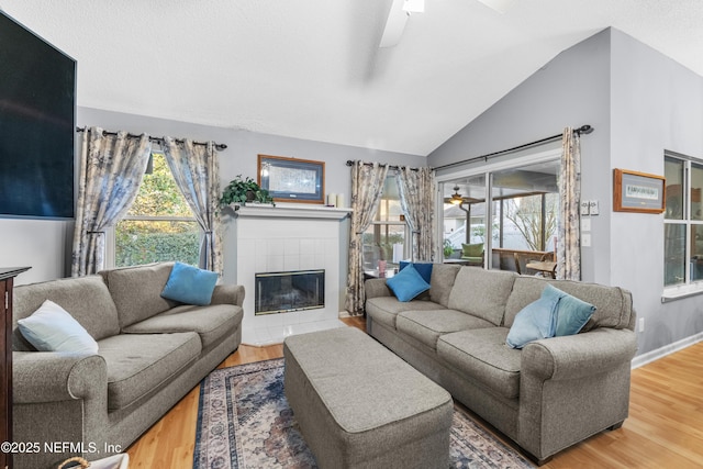 living room featuring lofted ceiling, wood-type flooring, a fireplace, and ceiling fan