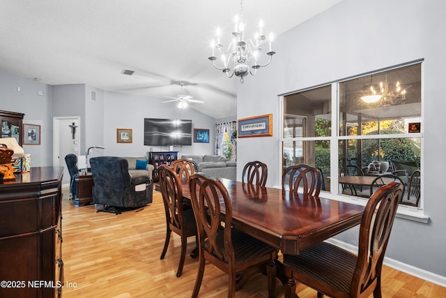 dining space with lofted ceiling, ceiling fan with notable chandelier, and hardwood / wood-style floors