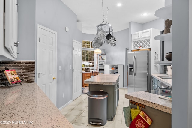 kitchen with backsplash, a kitchen island, stainless steel refrigerator with ice dispenser, white cabinetry, and hanging light fixtures