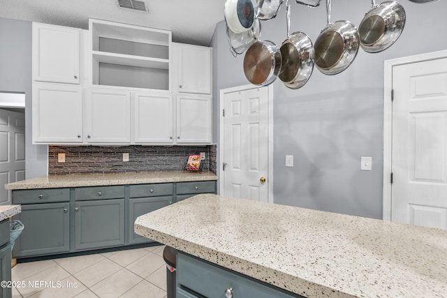 kitchen with light stone countertops, a textured ceiling, white cabinetry, backsplash, and light tile patterned floors