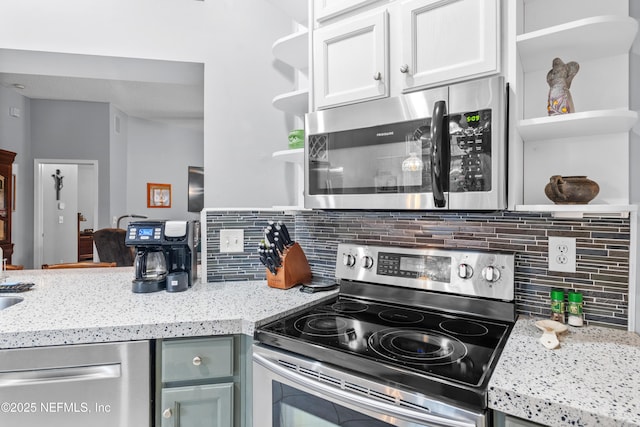 kitchen featuring white cabinets, backsplash, light stone countertops, and stainless steel appliances