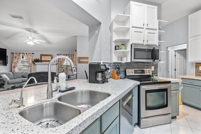 kitchen featuring white cabinets, stainless steel appliances, tasteful backsplash, sink, and ceiling fan