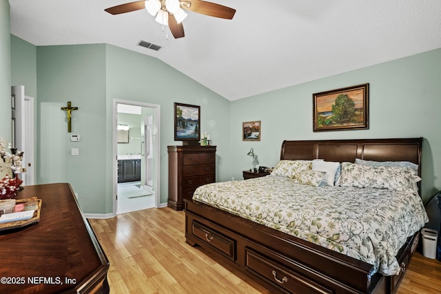 bedroom with light wood-type flooring, ceiling fan, ensuite bathroom, and lofted ceiling