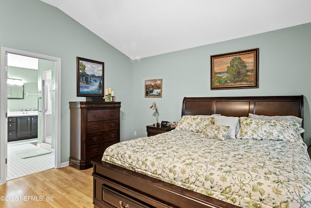 bedroom with vaulted ceiling, light hardwood / wood-style floors, and connected bathroom