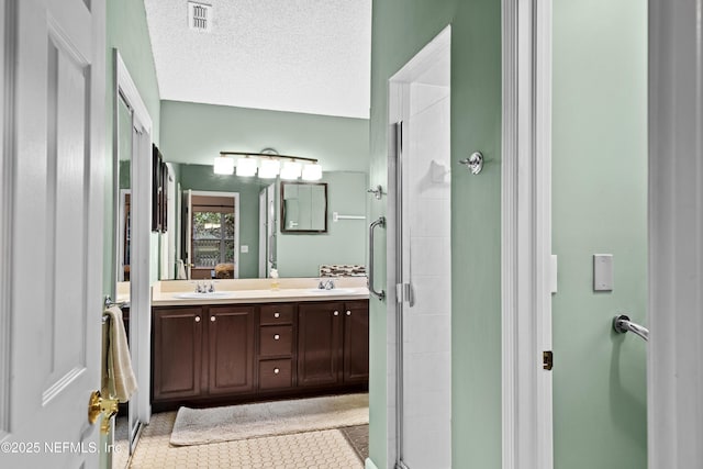 bathroom with a textured ceiling, an enclosed shower, and vanity