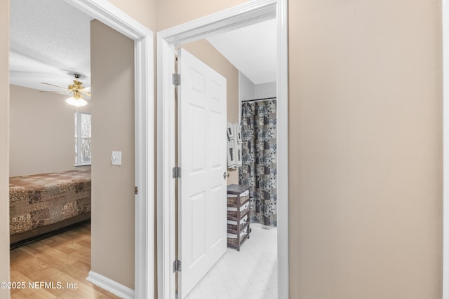 corridor with a textured ceiling and light hardwood / wood-style floors